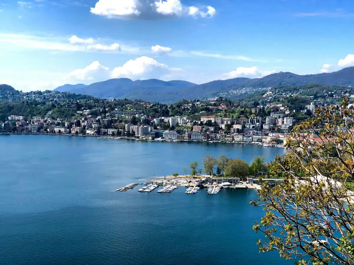 Aerial view of city buildings near body of water during daytime — Lugano, Switzerland
